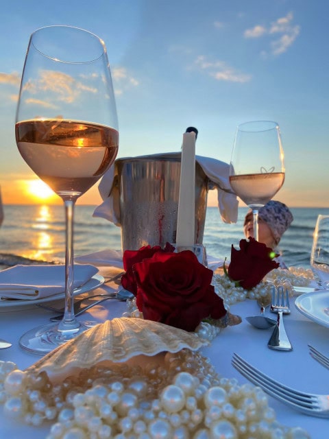 gedeckter Tisch mit Wein bei Sonnenuntergang am Strand des Strandhotel Fischlands