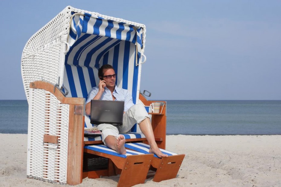 Mann sitzt mit Laptop und einer Tasse Kaffee im Strandkorb des Strandhotel Fischlands