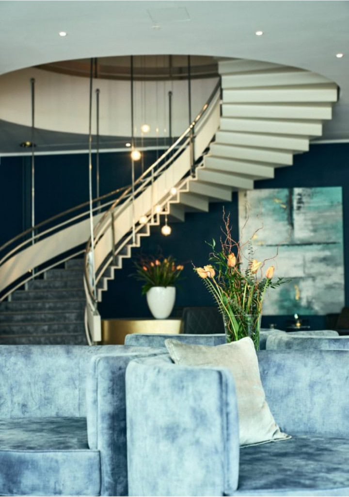 Wendeltreppe mit Sesseln in der Lobby des Strandhotel Fischlands