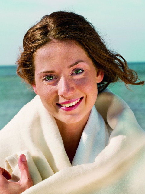 lächelnde junge Frau im Bademantel des Strandhotel Fischlands an der Ostsee