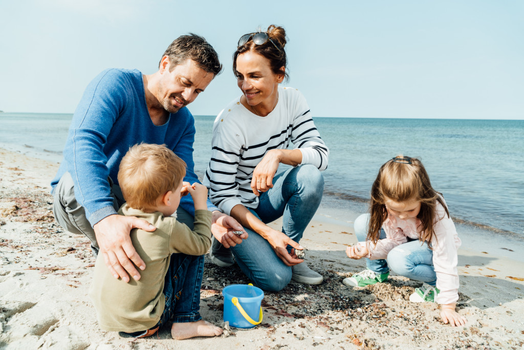 Familie sammelt Muscheln und Steine am Ostseestrand