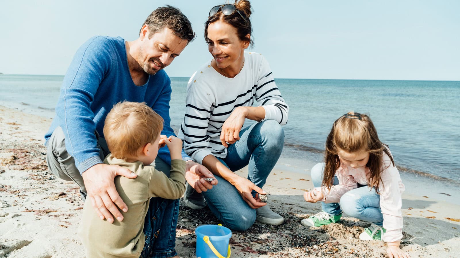 Familie sammelt Muscheln und Steine am Ostseestrand