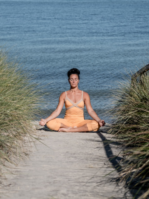 Yogalehrerin macht Yoga in den Dünen des Strandhotel Fischlands