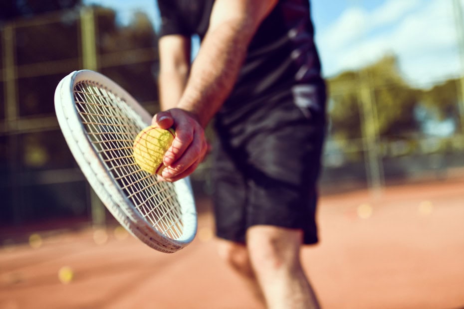 Mann macht Aufschlag beim Tennis im Strandhotel Fischland