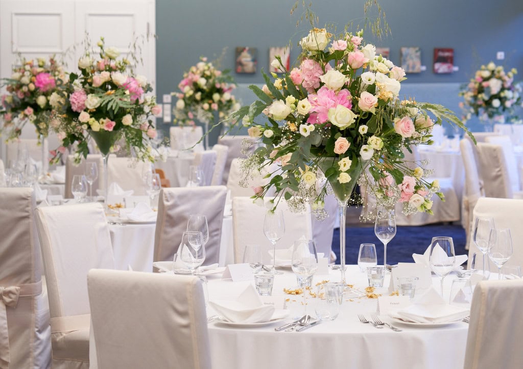 gedeckte runde Tische mit Blumendekoration für Hochzeit im Strandhotel Fischland