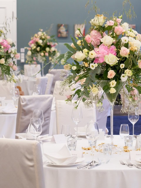 gedeckte runde Tische mit Blumendekoration für Hochzeit im Strandhotel Fischland