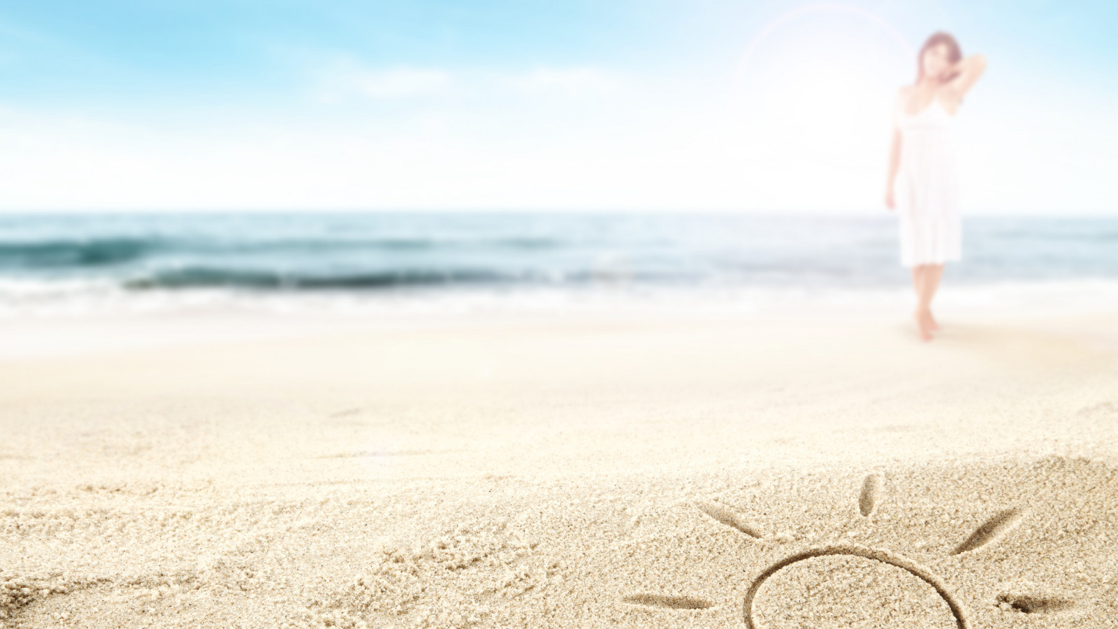 in den Sand gemalte Sonne mit Frau und Ostsee im Hintergrund