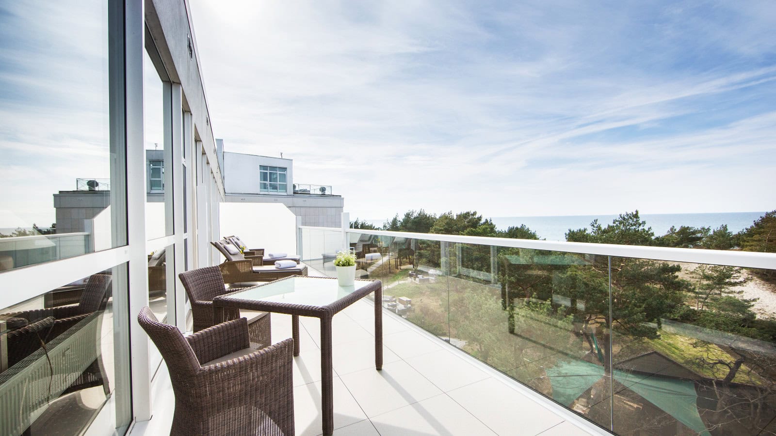 Sonnenliegen und Tisch mit Stühlen auf einem Balkon im Strandhotel Fischland