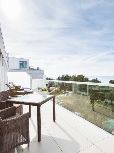 Sonnenliegen und Tisch mit Stühlen auf einem Balkon im Strandhotel Fischland