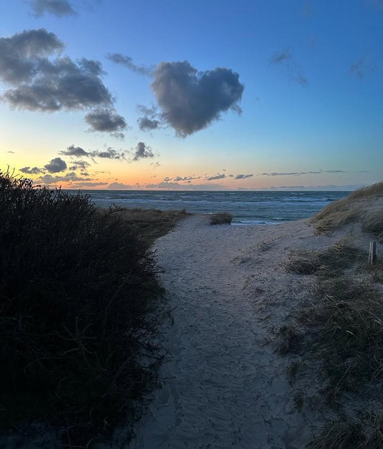 Weg zum Strand bei Sonnenuntergang mit Herzwolke am Himmel