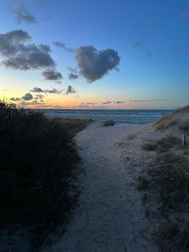 Weg zum Strand bei Sonnenuntergang mit Herzwolke am Himmel