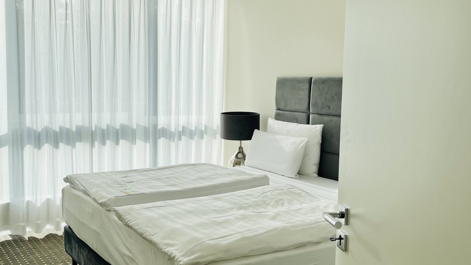 Doppelbett mit stilvoller Nachttischlampe im Schlafbereich einer Suite im Strandhotel Fischland