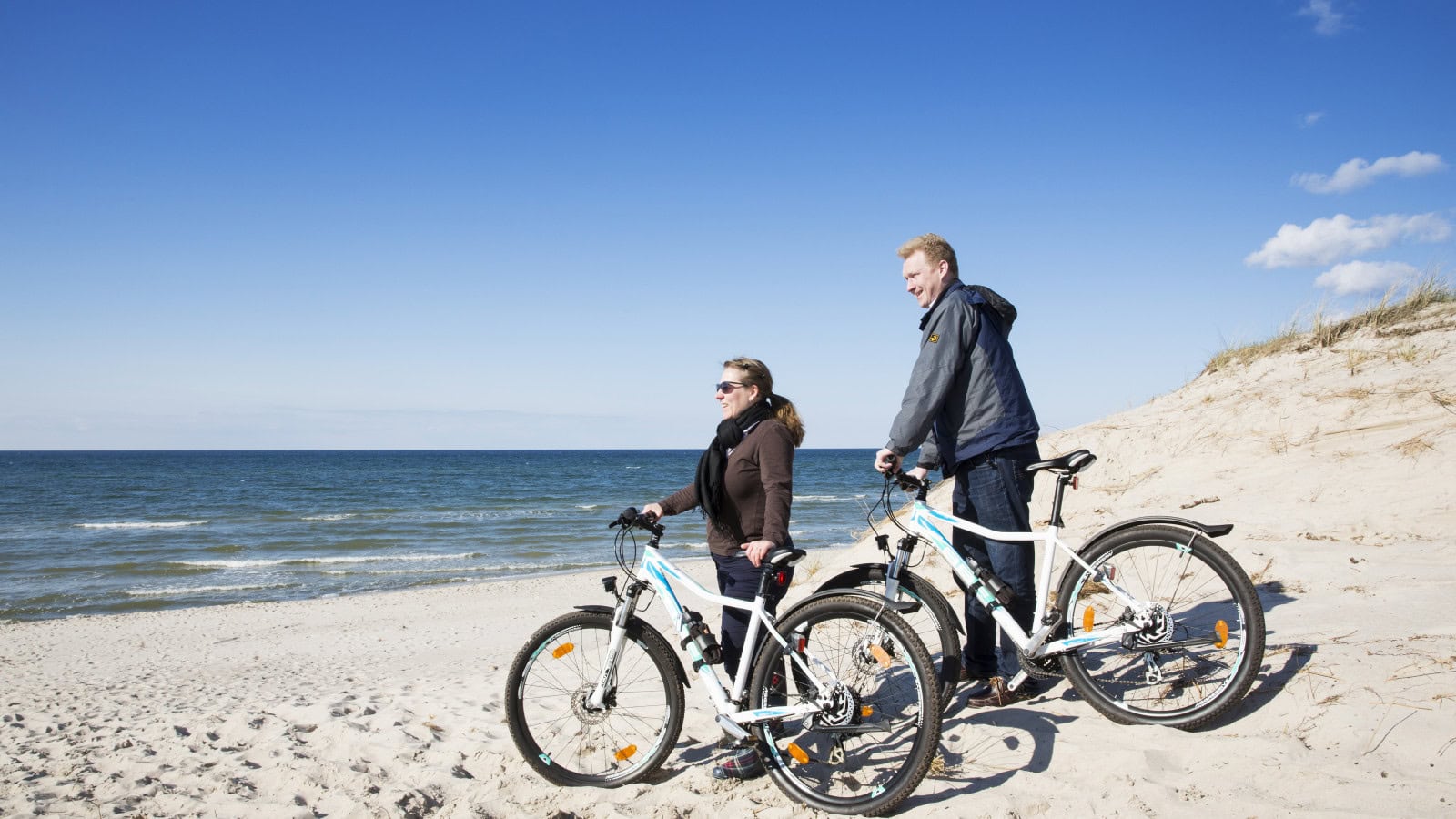 Paar mit Mountainbikes des Strandhotel Fischlands am Strand