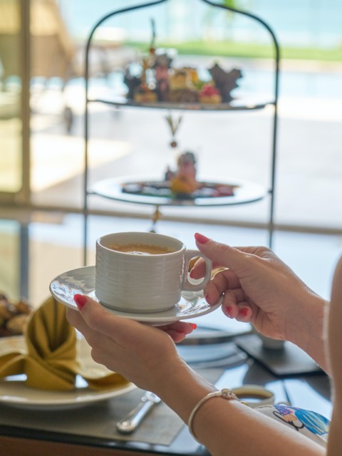 Frau hält einen Kaffee in der Hand am Frühstücksbuffet im Strandhotel Fischland