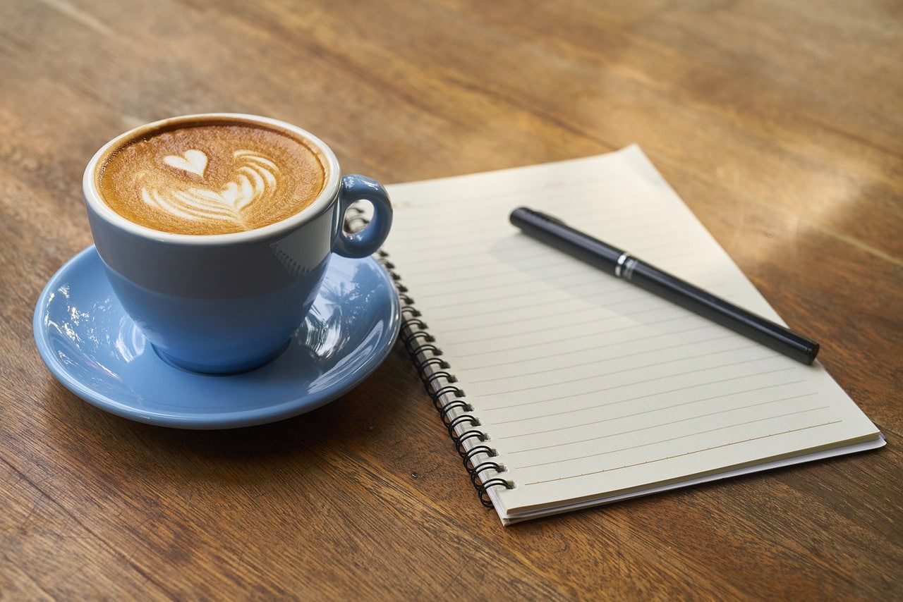 Kaffeegenuss, Kaffeetasse mit einen Block mit Stift zum notieren von Gedanken